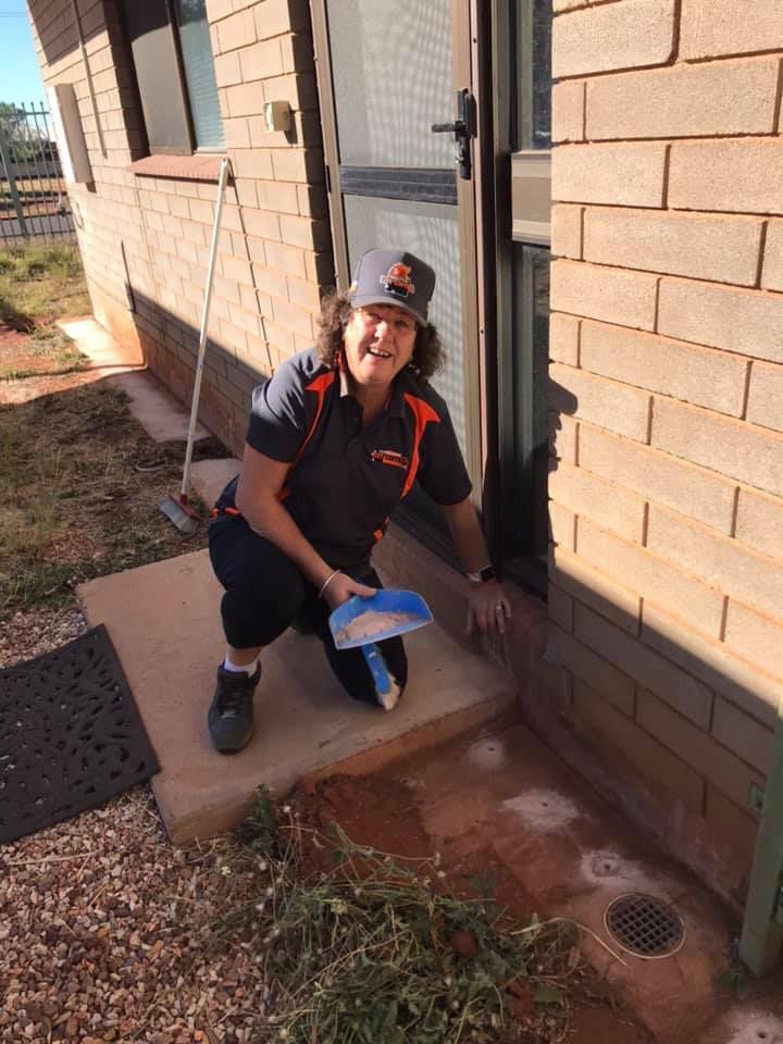 A Woman Treating Pests in Front of a House  — Territory Pest Control In Winnellie, NT