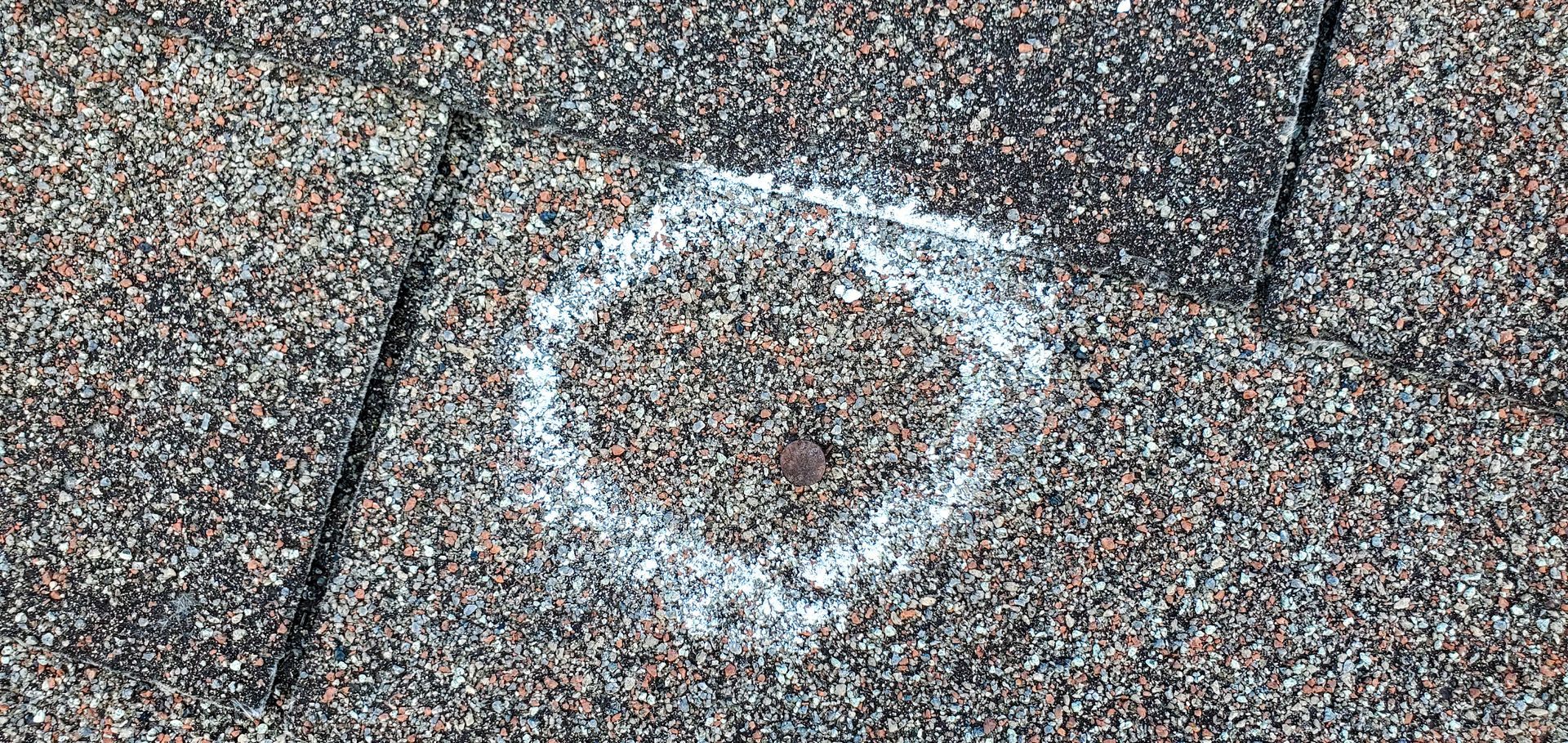 White chalk circle marking on a speckled brick or pavement surface
