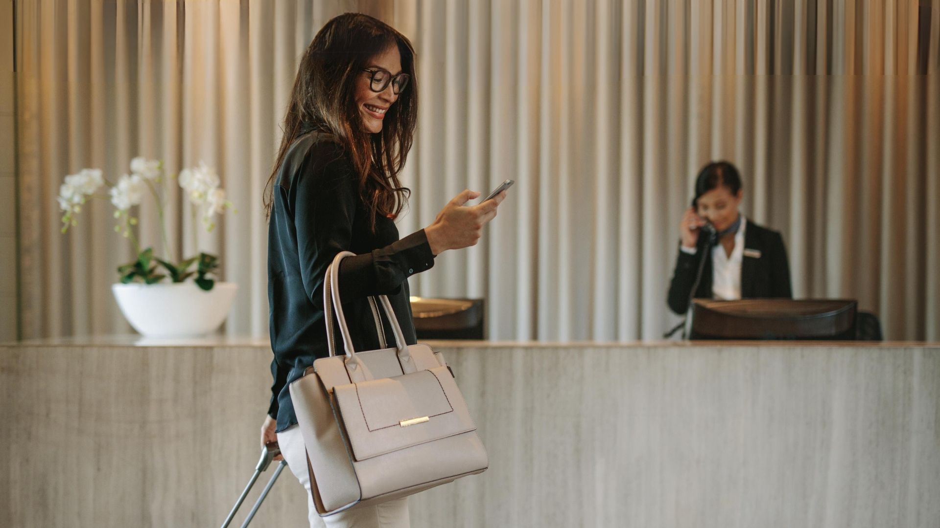 A woman walking through a hotel lobby looking at a campaign from IP Targeting Advertising 