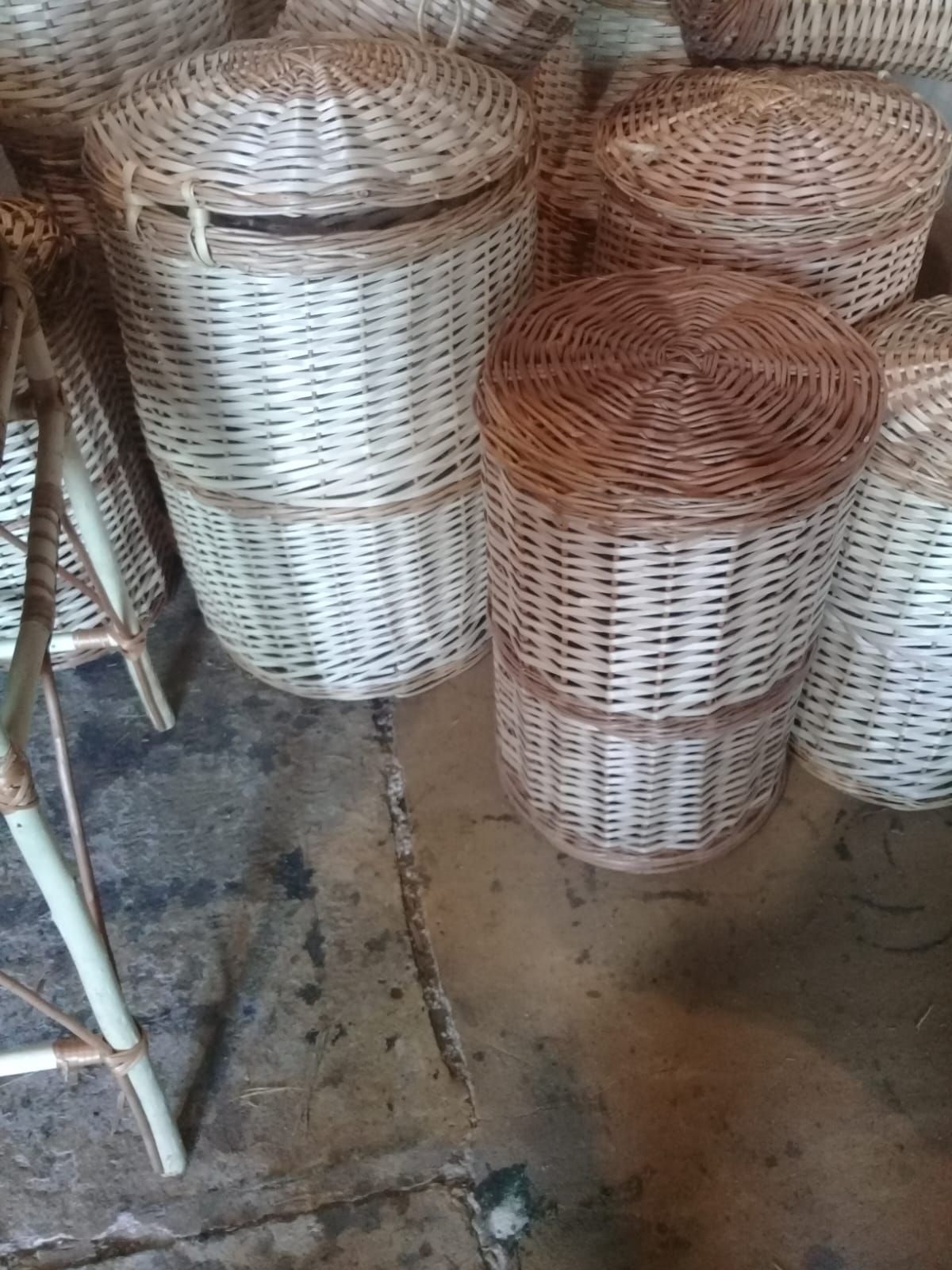 Varias cestas redondas de mimbre tejido con tapa, colocadas sobre un suelo de piedra rústica.