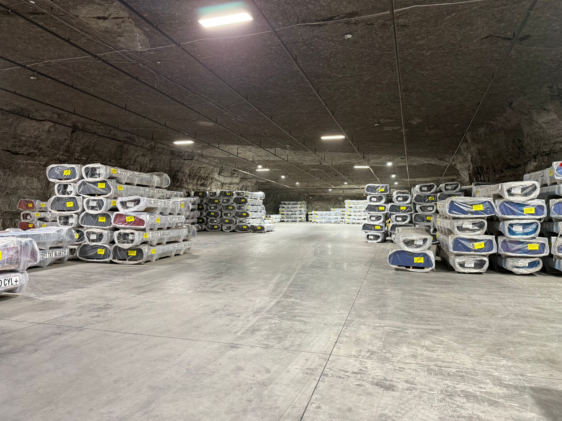 Warehouse aisle with stacked blue-and-gray containers under ceiling lights