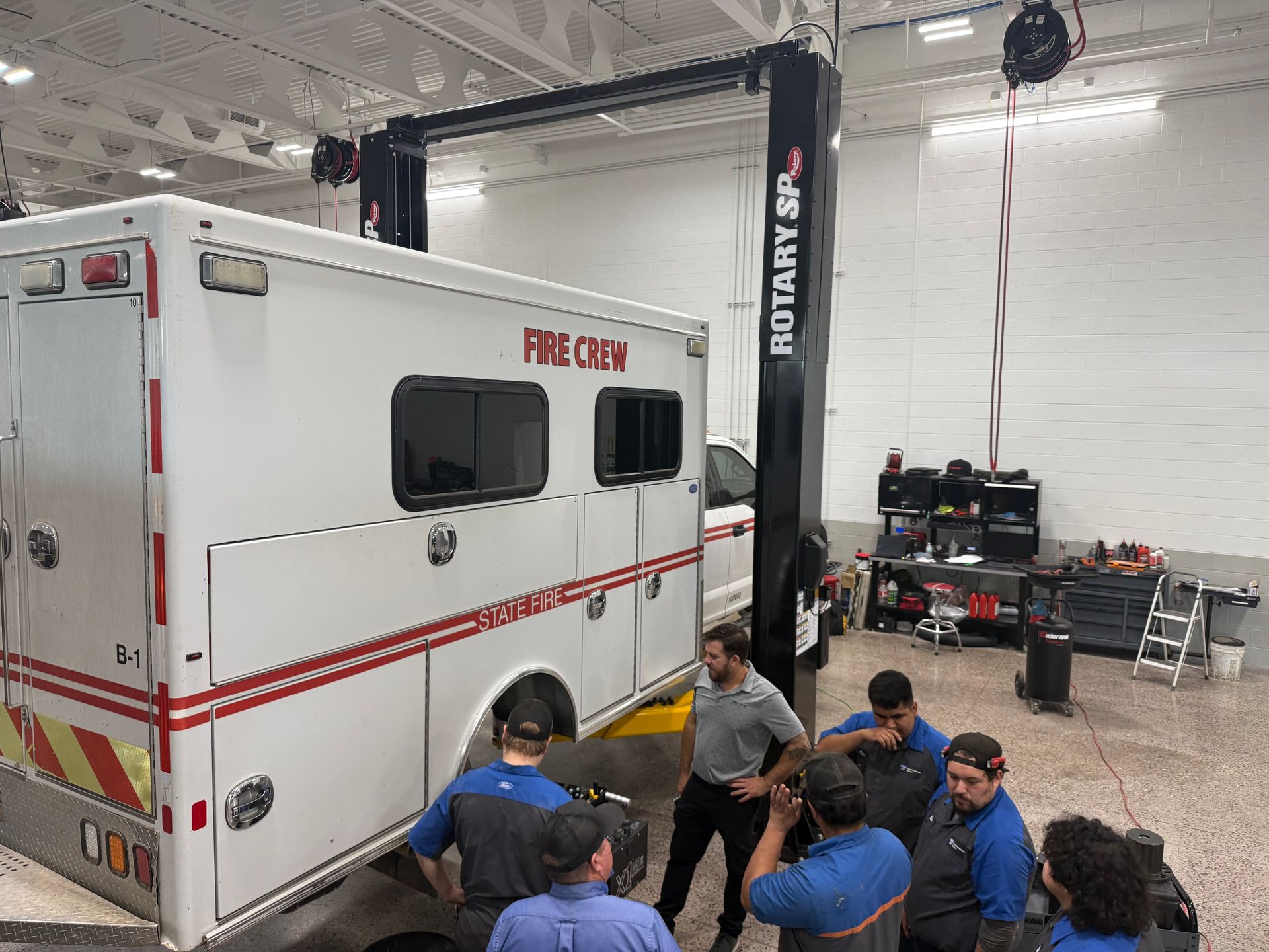 Paramedics lifting a patient on a stretcher beside an ambulance inside a garage bay