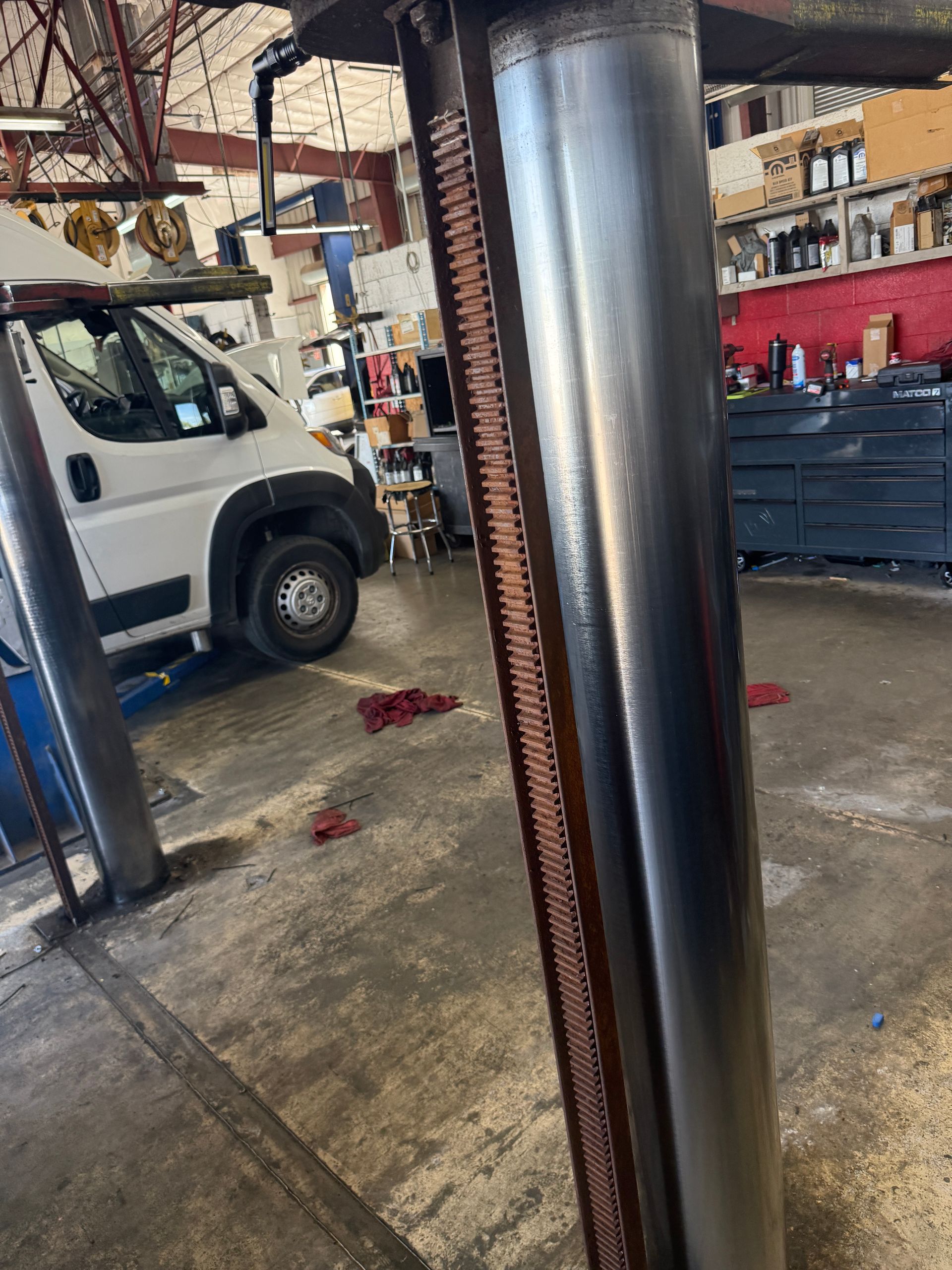 Warehouse interior with a white van, metal columns, and stacked equipment on a concrete floor