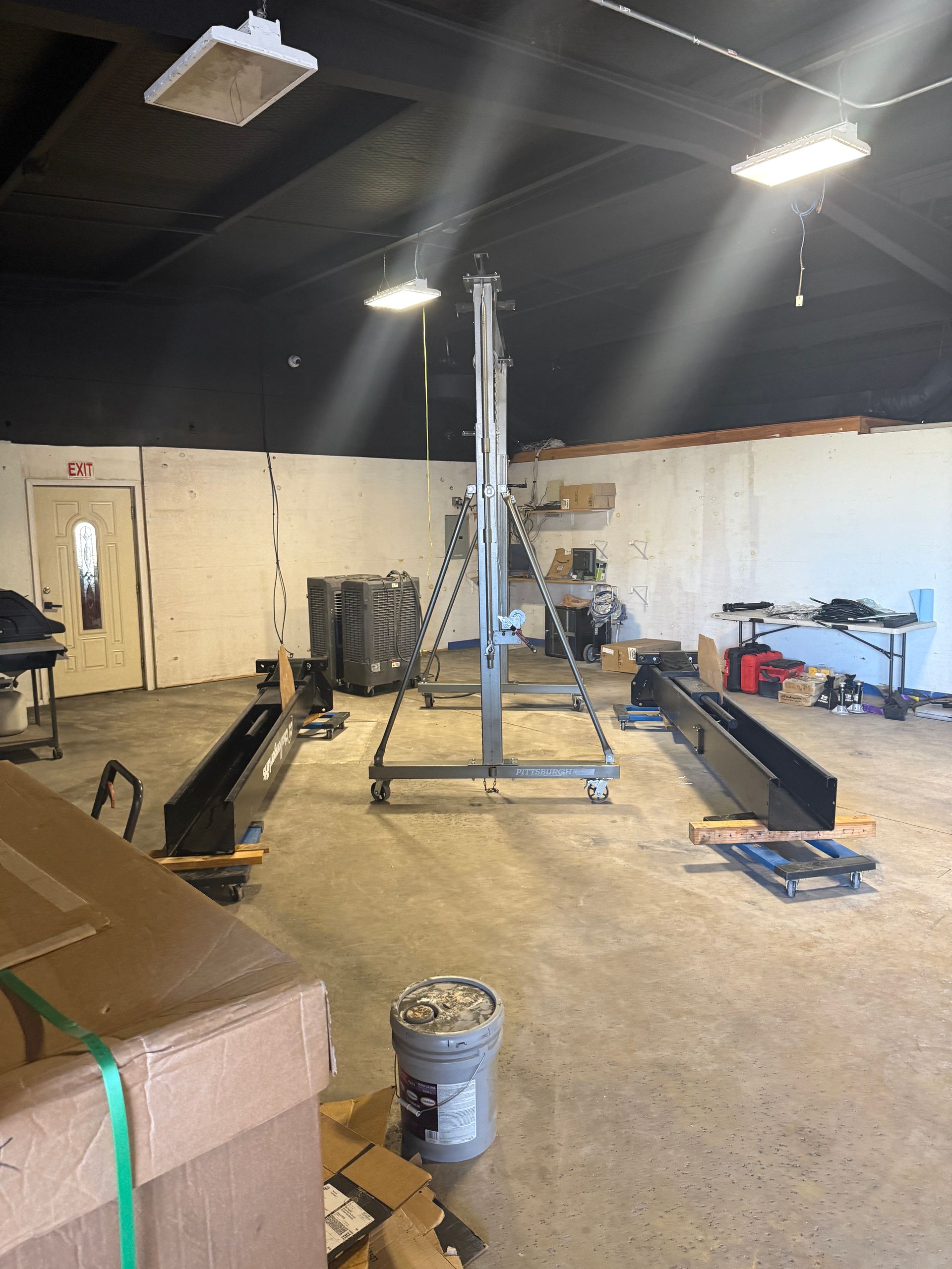 Blue two-post car lift in an auto shop, with a white pickup truck inside the bay.