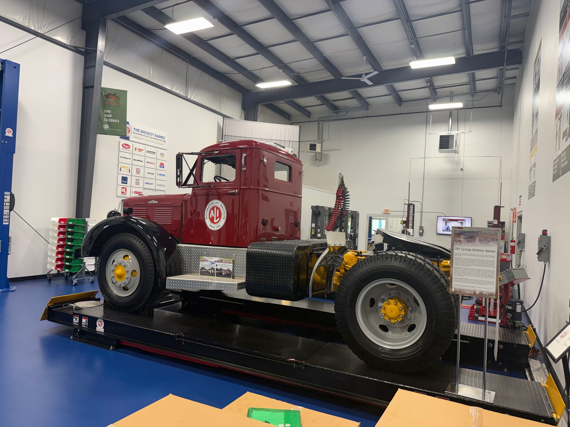 Auto repair shop bay with blue vehicle lift, red walls, and garage equipment