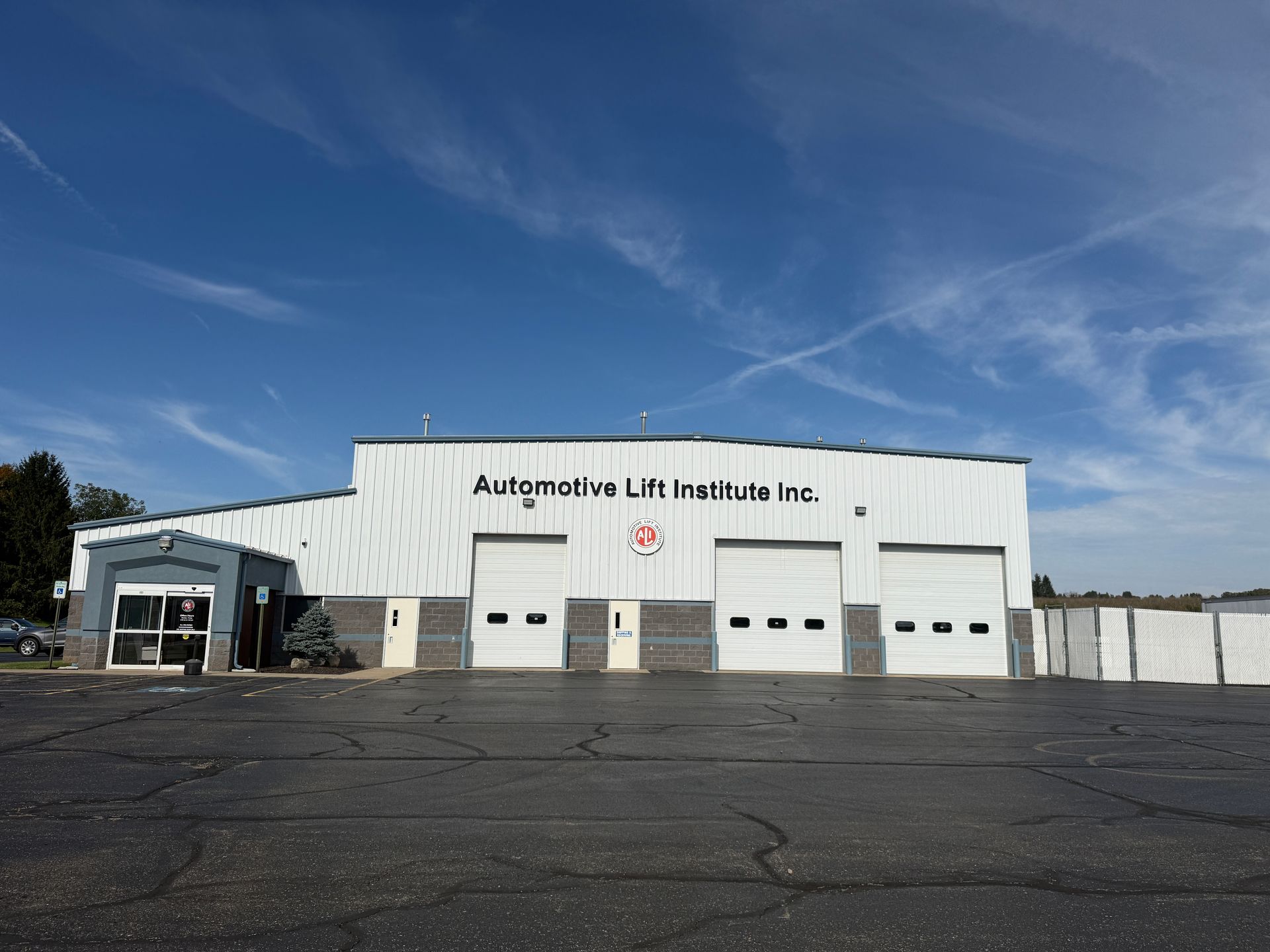 Empty auto shop bay with a blue two-post car lift and a ladder on the left inside a concrete garage.