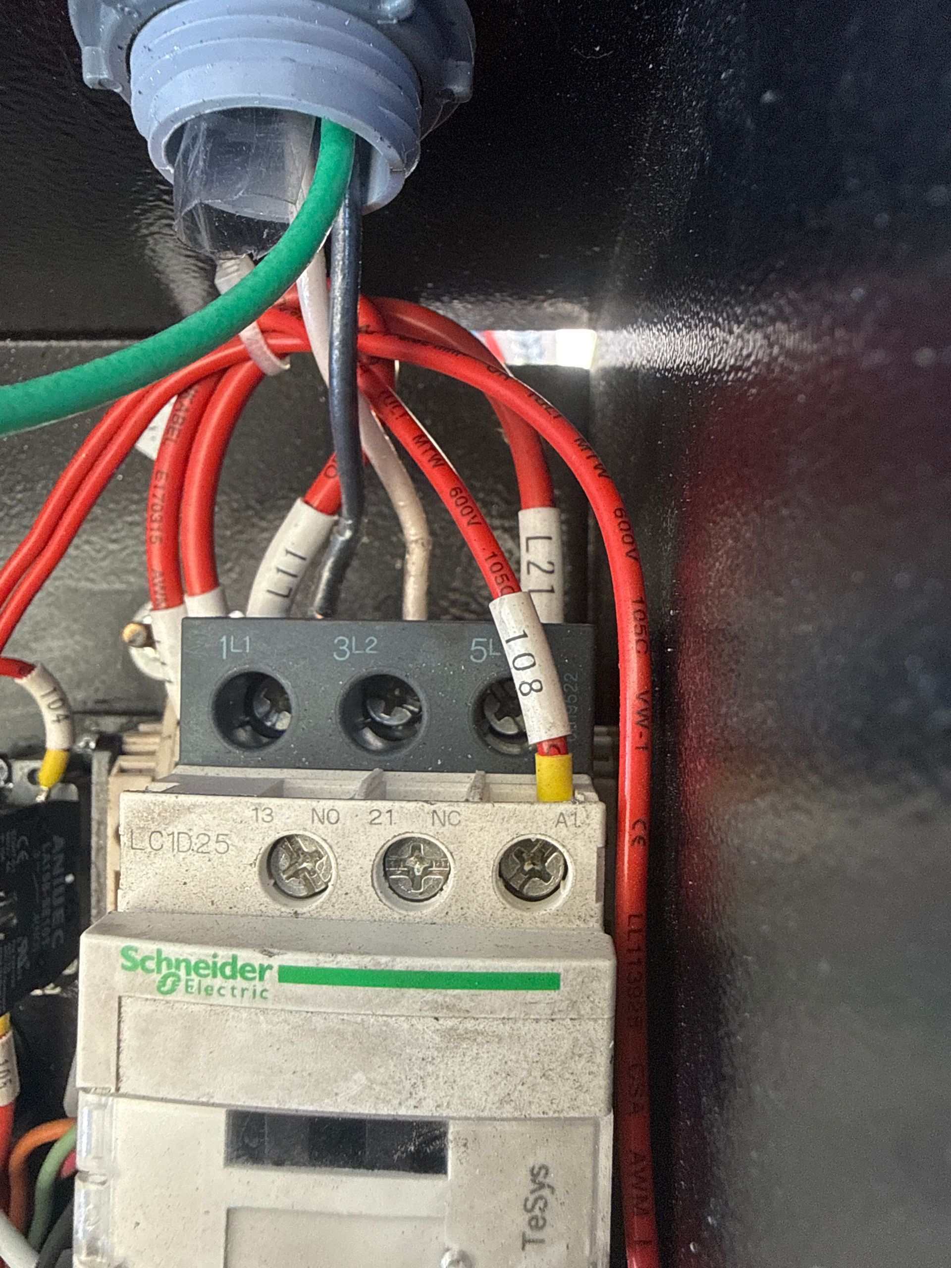 Close-up of a Schneider Electric circuit breaker with red, green, and black wires inside an electrical panel