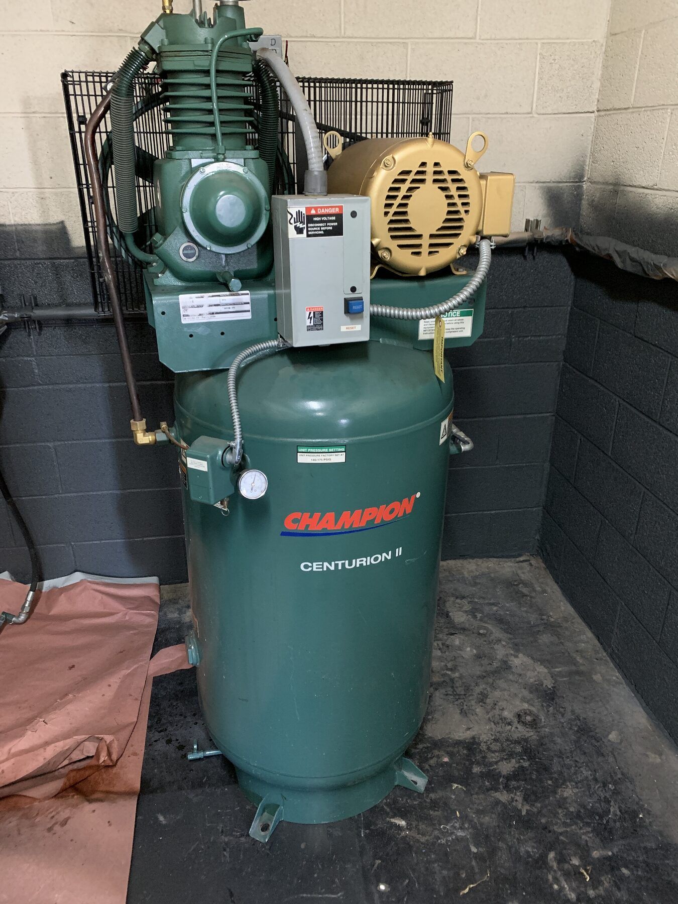 Green Champion air compressor with two motor units and gauges in an industrial garage.