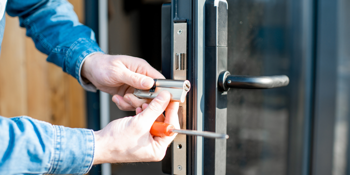 A man is fixing a door lock with a screwdriver.