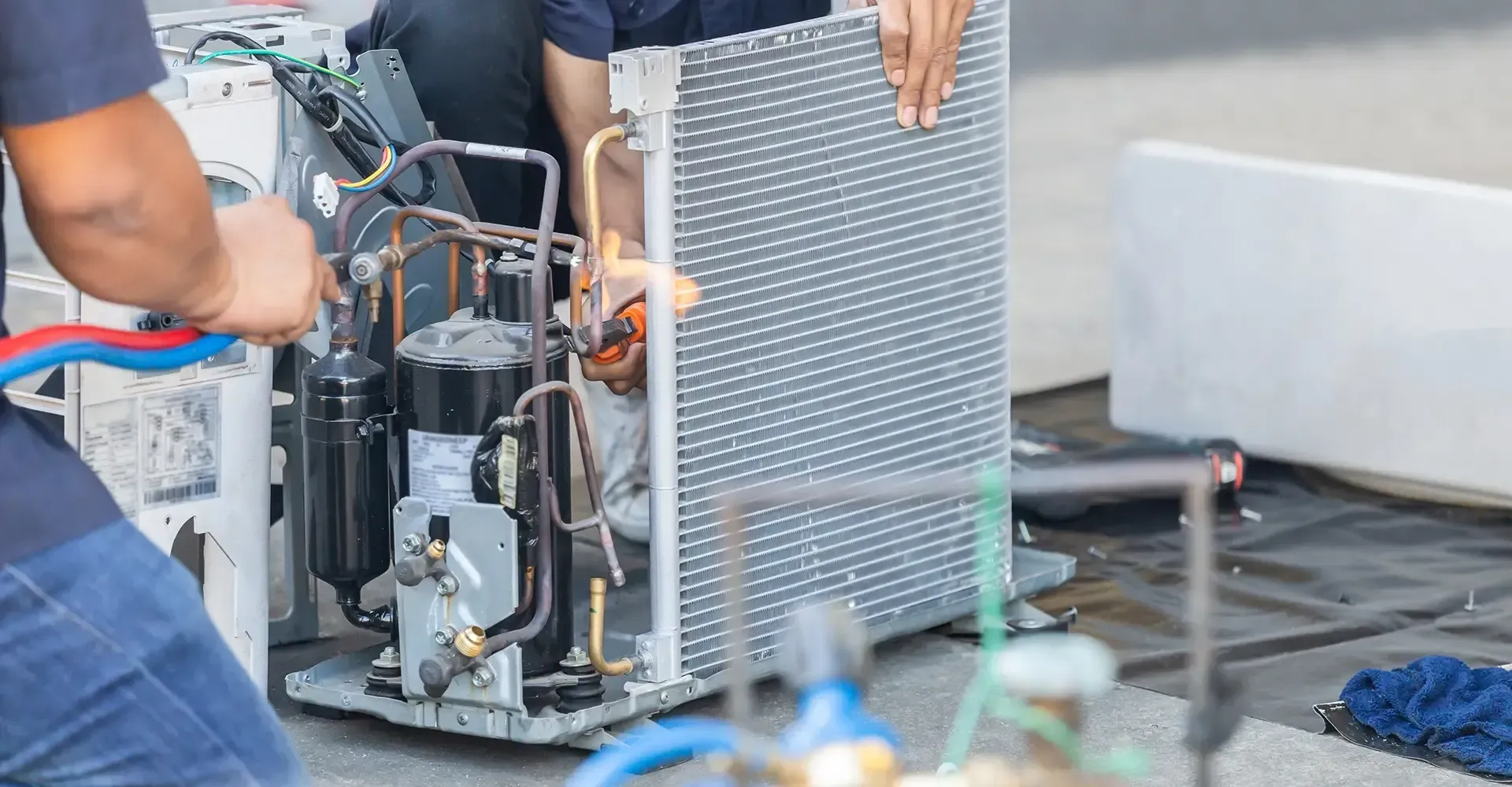 A man is working on an air conditioner with a wrench.
