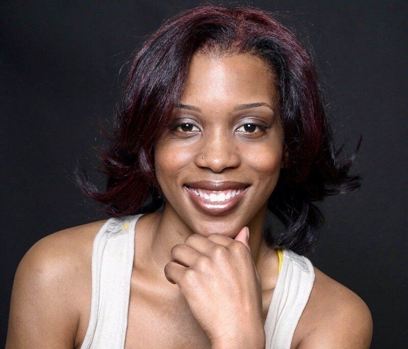 A woman is smiling with her hand on her chin