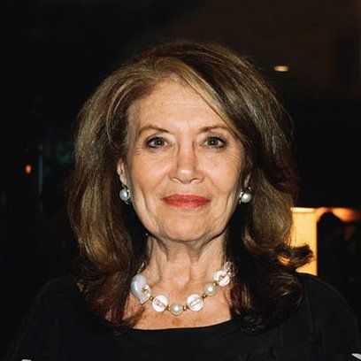 A woman wearing a necklace and earrings is smiling for the camera.