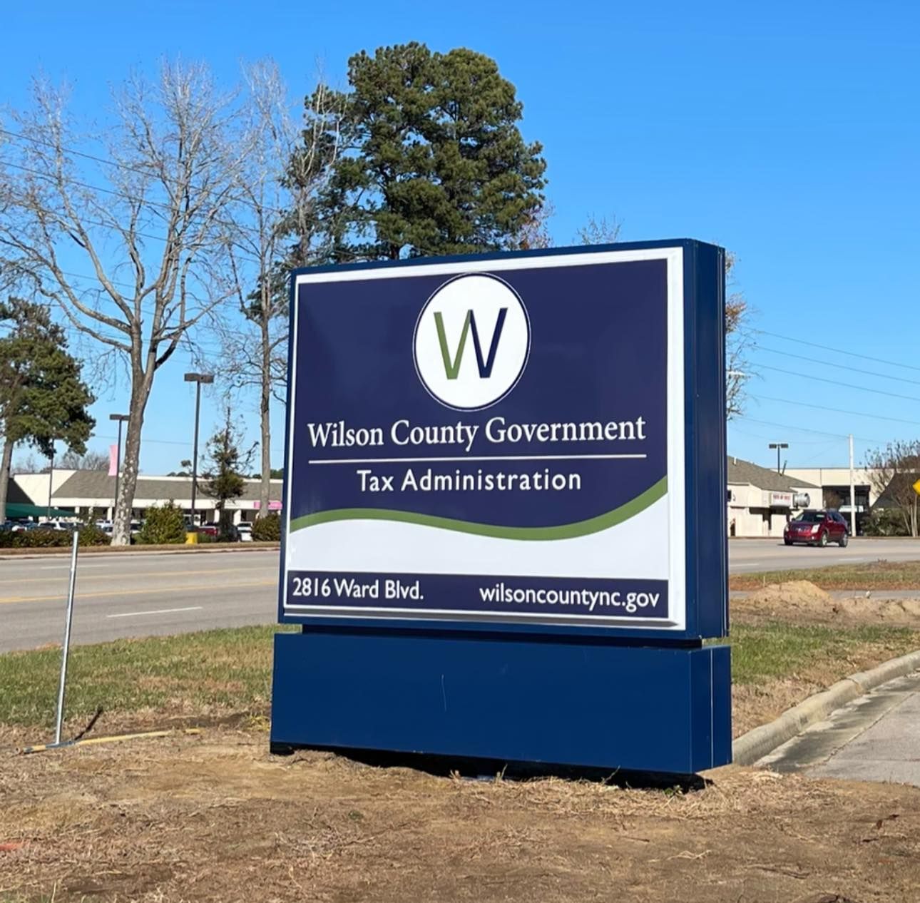 Blue sign for Wilson County Government Tax Administration. Sign features the county logo and address.