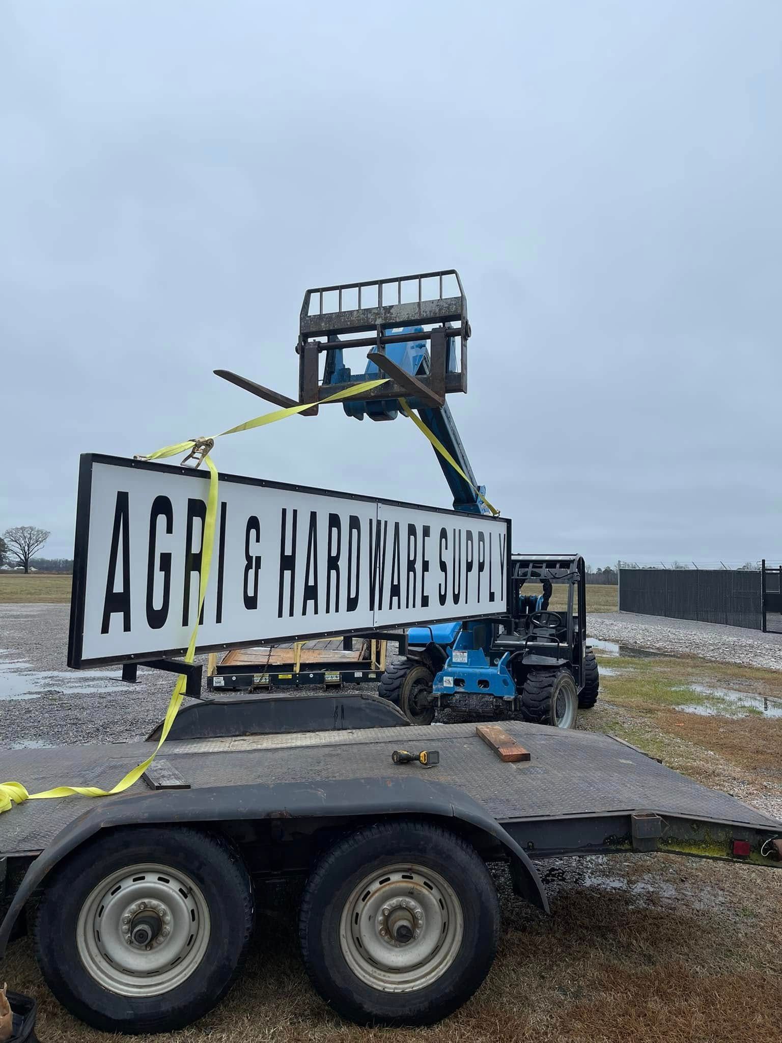 A blue telehandler lifts a sign for 