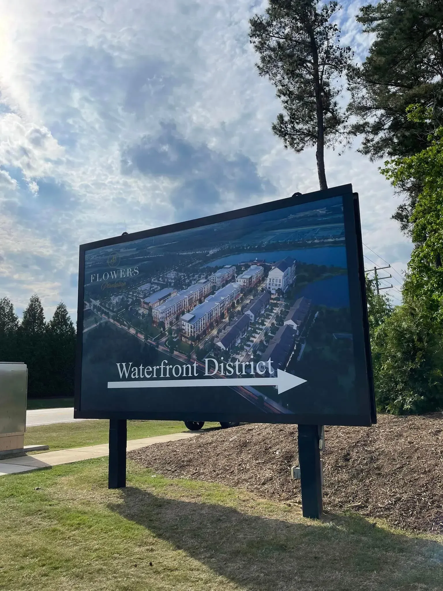 Sign for Waterfront District with a digital display showing a waterfront aerial view, with a white arrow.