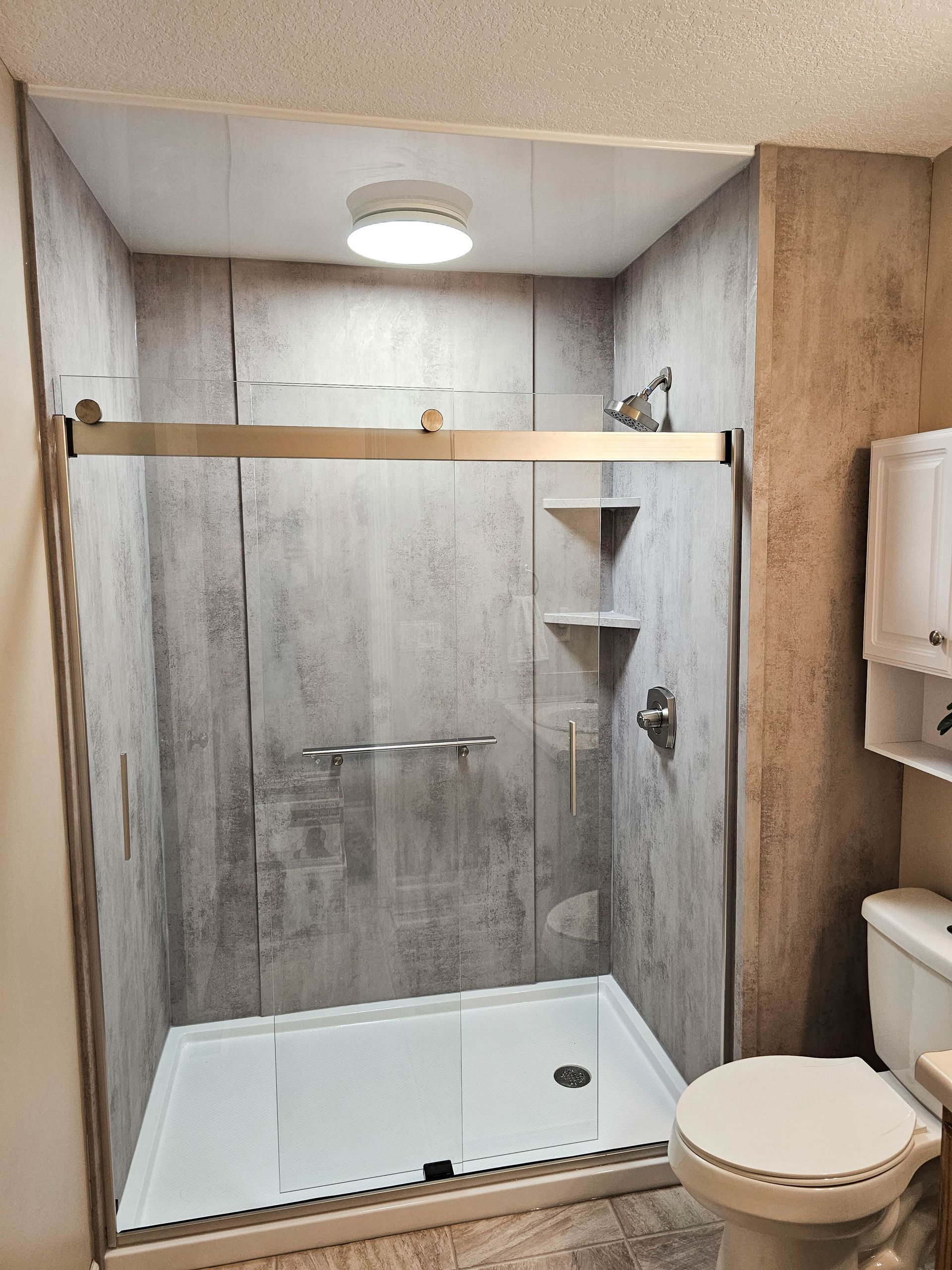 Modern bathroom with walk-in shower, white toilet, and wood-accent walls