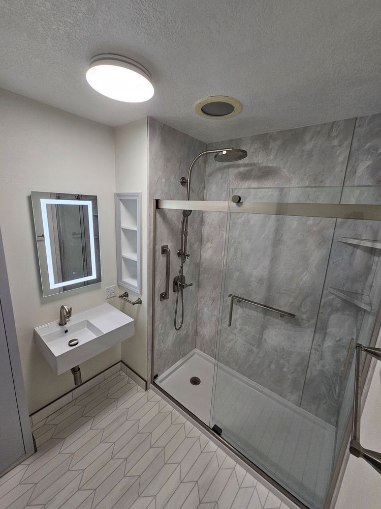Accessible bathroom with roll-in shower, wall-mounted sink, mirror, and grab bars