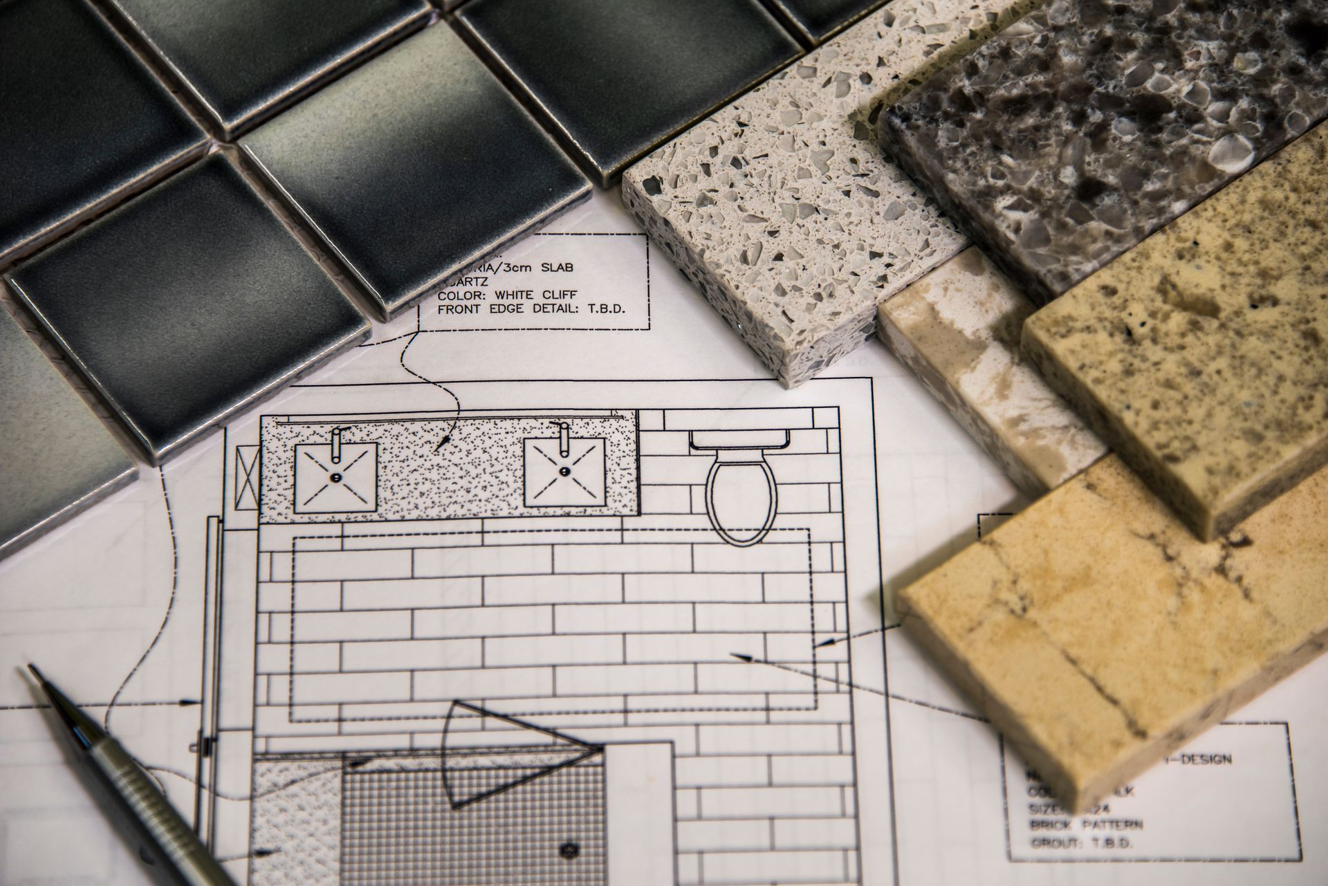 Tile and countertop samples arranged on top of a bathroom renovation blueprint. Tile and countertop samples arranged on top of a bathroom renovation blueprint.
