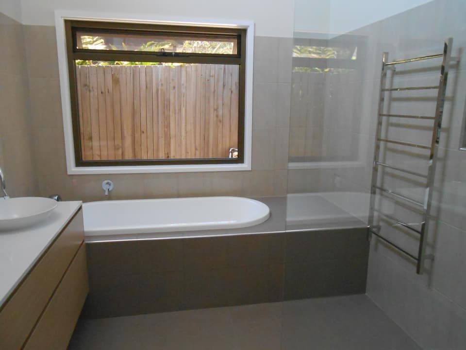 A Bathroom With A Bathtub A Sink And A Window — Scott Graham Building Services In Mermaid Beach, QLD