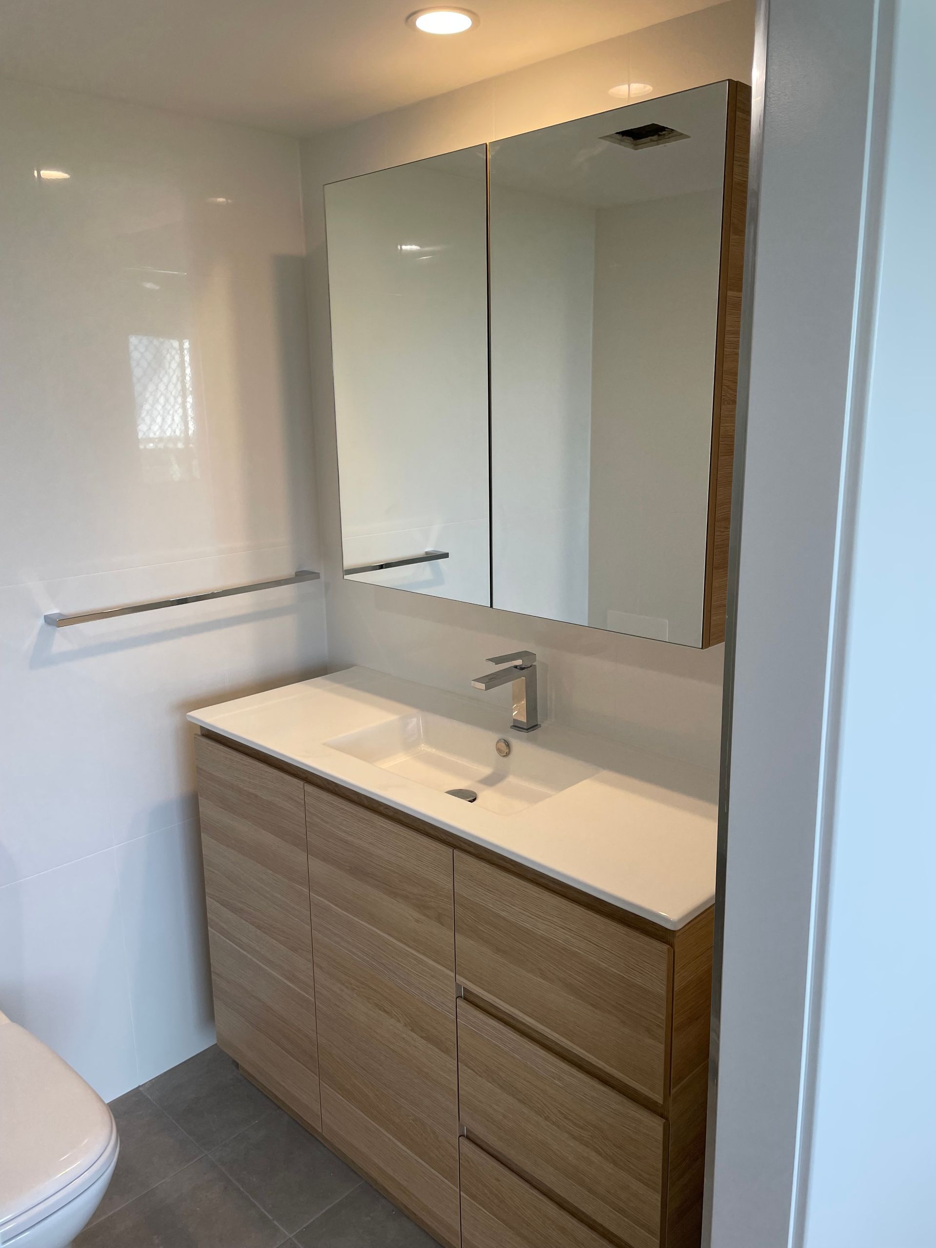 A Bathroom With a Sink, Mirror and Toilet  — Scott Graham Building Services In Bilambil Heights, NSW 