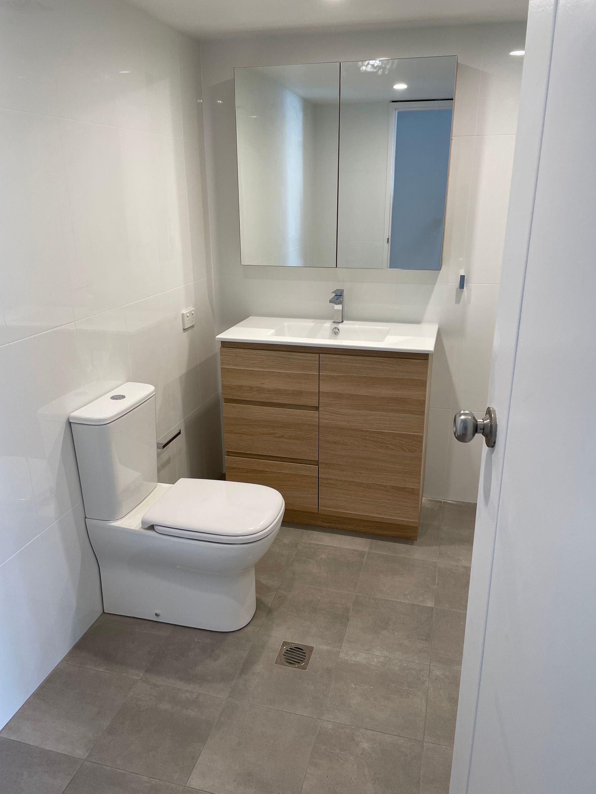 A Bathroom With a Toilet, Sink and Mirror  — Scott Graham Building Services In Bilambil Heights, NSW 