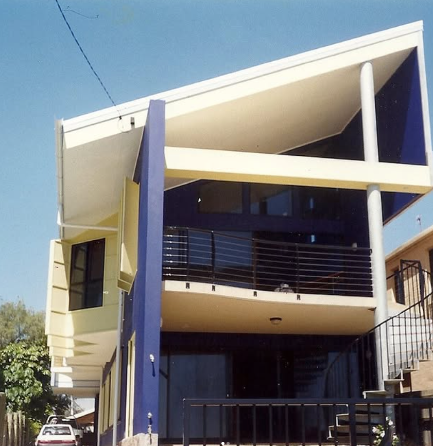 A blue and white house with a balcony and stairs