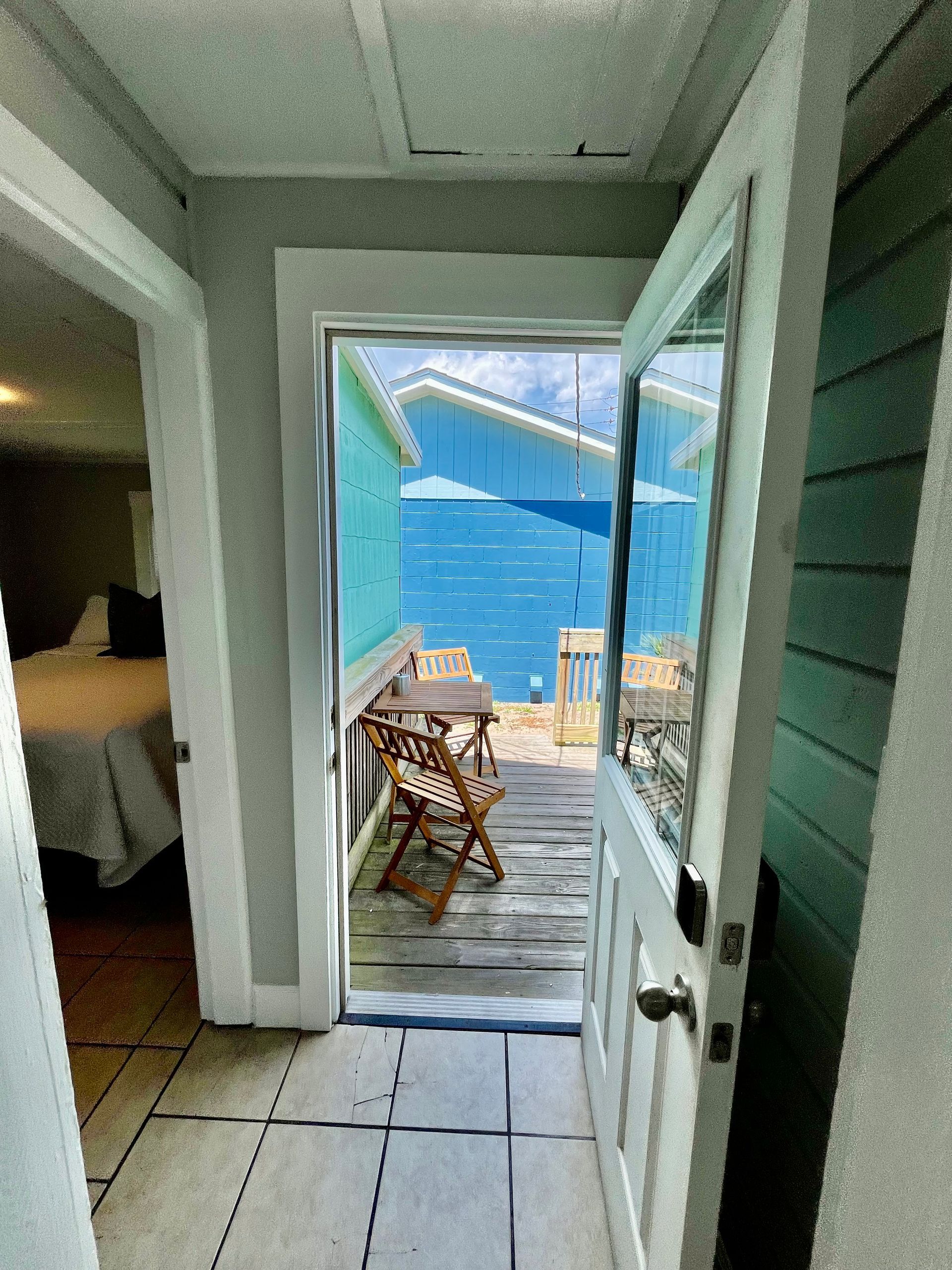 A view from a guest room at Seabirds Motel at Kure Beach looking out onto a small private deck with seating. The bright, outdoor setting enhances the motel's pet-friendly environment and provides a relaxing space for guests in North Carolina.