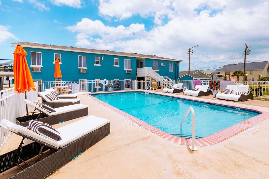 A vibrant outdoor pool area at Seabirds Motel at Kure Beach with lounge chairs, umbrellas, and a sparkling blue pool. This amenity enhances the motel's appeal for a relaxing, pet-friendly stay in North Carolina.