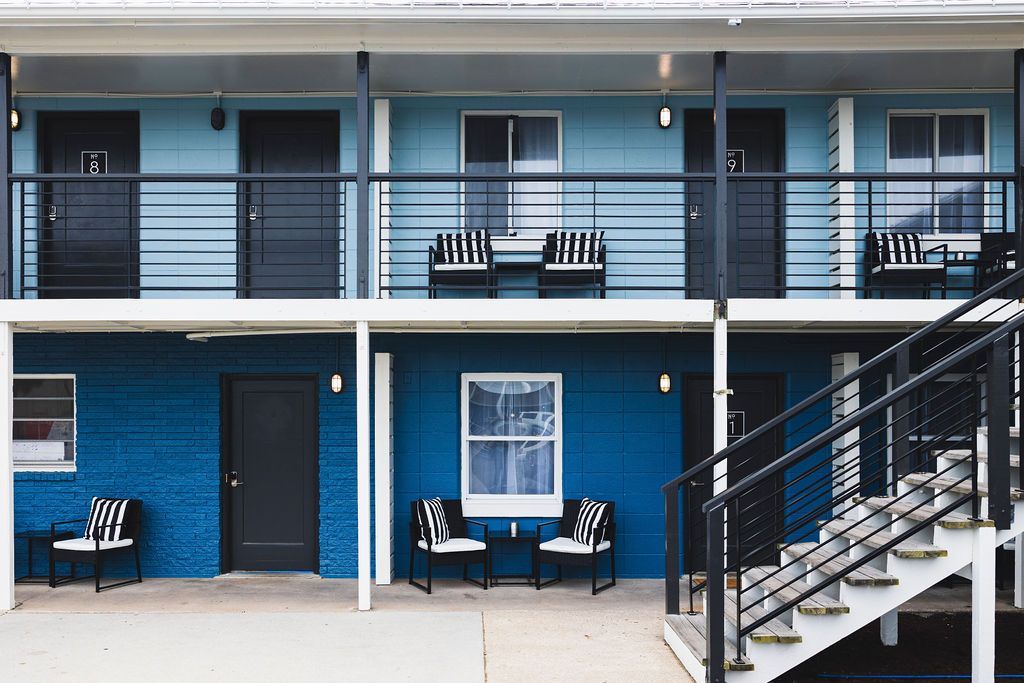 An exterior view of Seabirds Motel at Kure Beach showcasing two stories of guest rooms with balconies and a central courtyard. The building's design reflects a welcoming and pet-friendly atmosphere for guests in North Carolina.