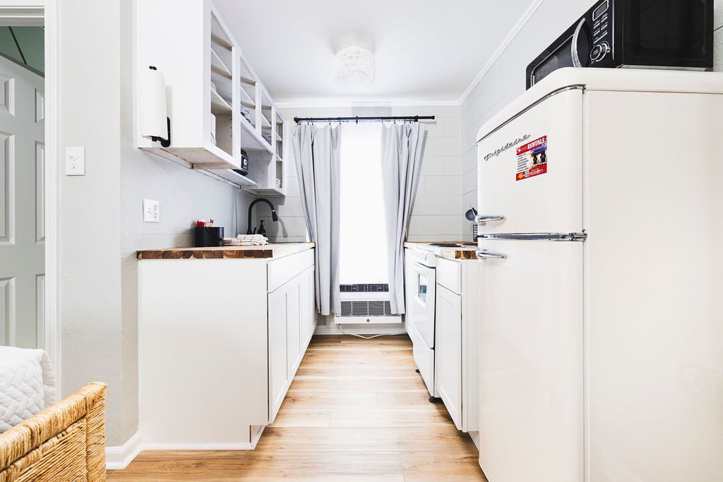  A compact, fully equipped kitchen at Seabirds Motel at Kure Beach, complete with a retro-style refrigerator, microwave, and ample counter space. This kitchen provides all the essentials for guests to prepare their meals during a pet-friendly North Carolina lodging experience.