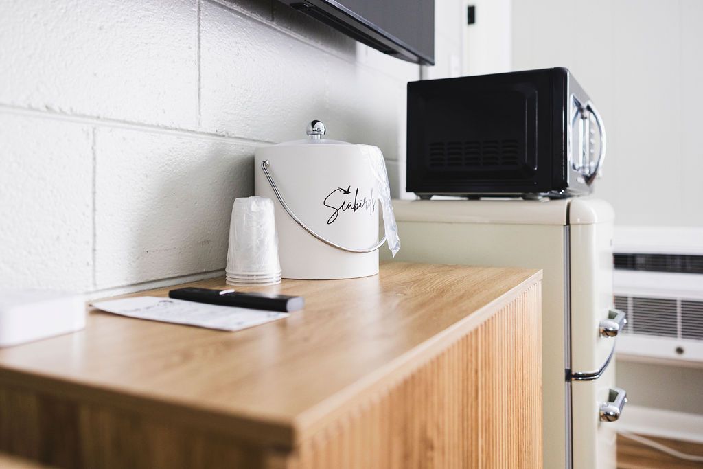  A compact room at Seabirds Motel at Kure Beach with a small microwave, mini-fridge, and coffee maker on a wooden cabinet. The room offers convenient amenities for a pet-friendly lodging experience in North Carolina.