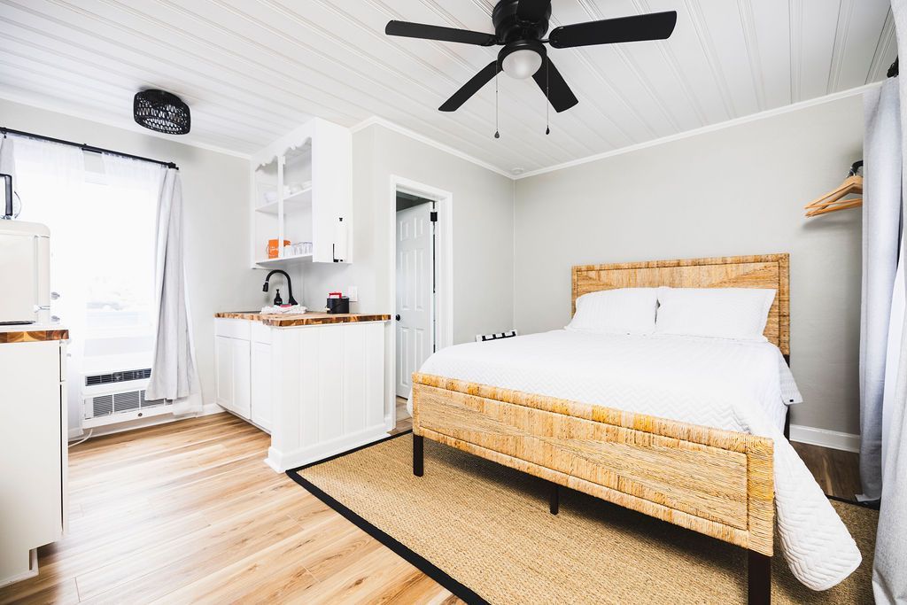 A bright guest room at Seabirds Motel at Kure Beach with a queen-sized bed, white linens, and minimalist decor. This room offers a comfortable environment for a pet-friendly stay in North Carolina.