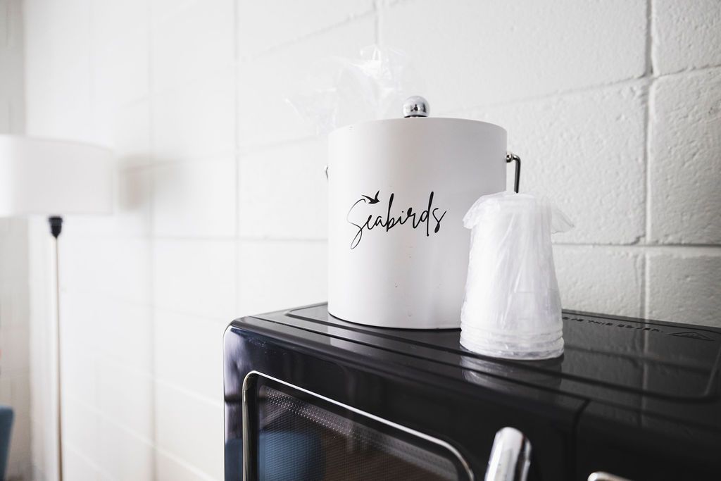 A close-up of a small beverage station in a room at Seabirds Motel at Kure Beach with a coffee maker and glasses. This amenity adds convenience to a pet-friendly lodging experience in North Carolina.