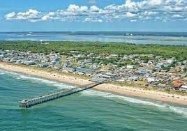 An aerial view of Kure Beach, North Carolina, showcasing the coastline, pier, and surrounding community. This image captures the scenic beauty and convenient location near Seabirds Motel, ideal for a pet-friendly beachside lodging experience.