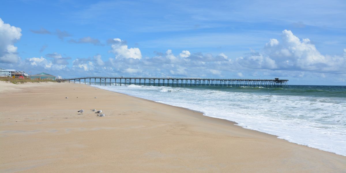 Distant view of Kure Beach Pier - seabirds on the sand
