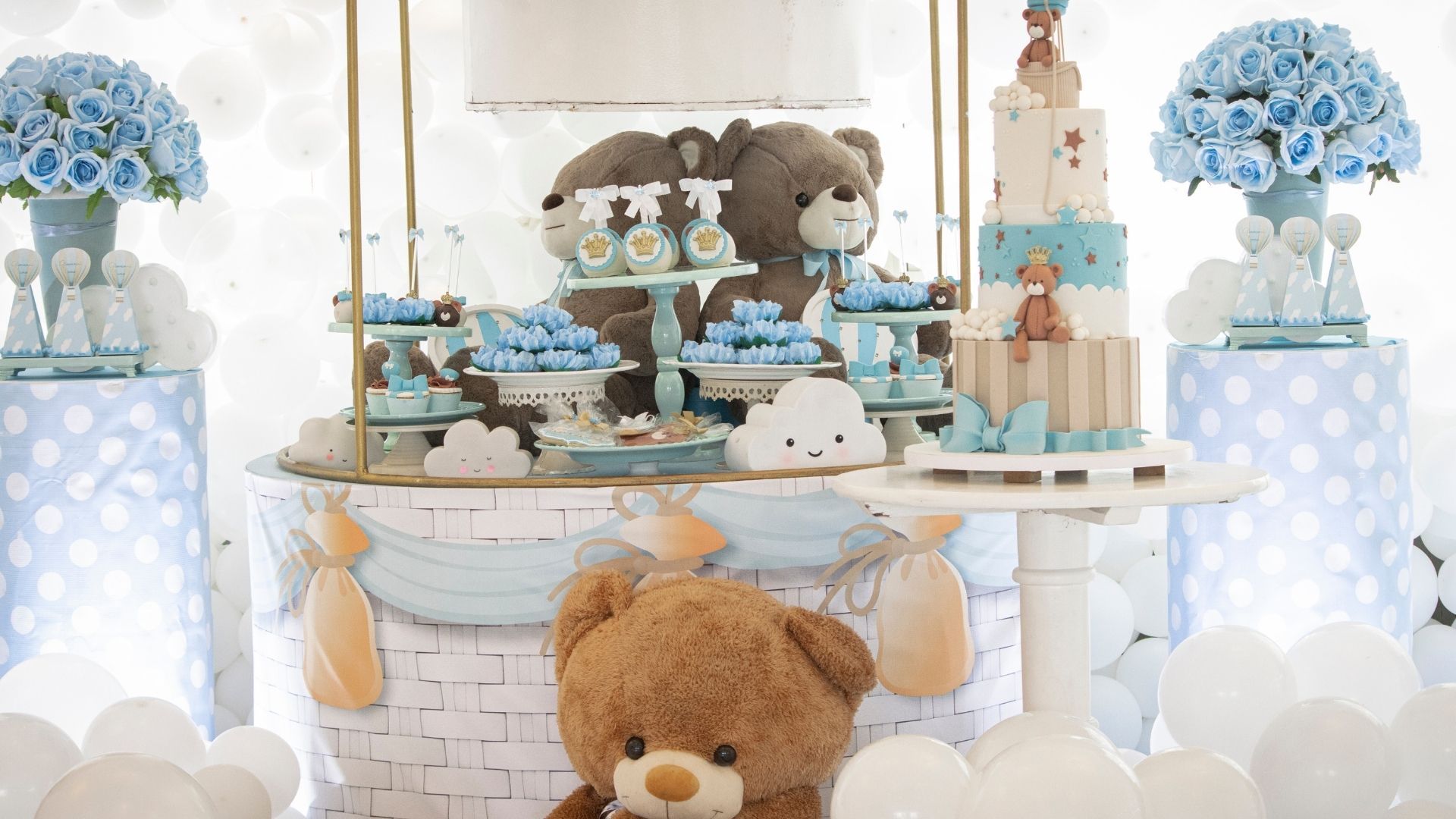 Teddy bear-themed dessert table with blue and white decorations, balloons, and plush bears at a party setup