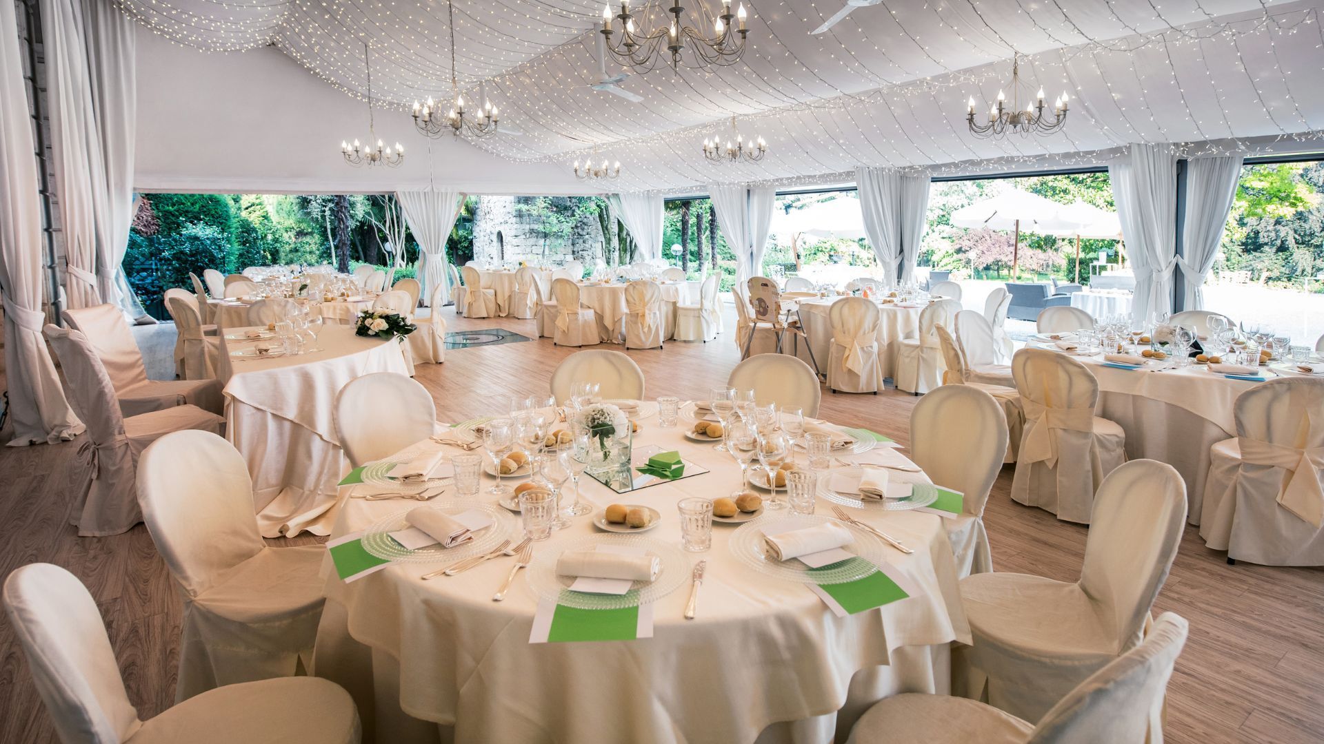 Elegant banquet tent with round, white-clothed tables set for a formal event