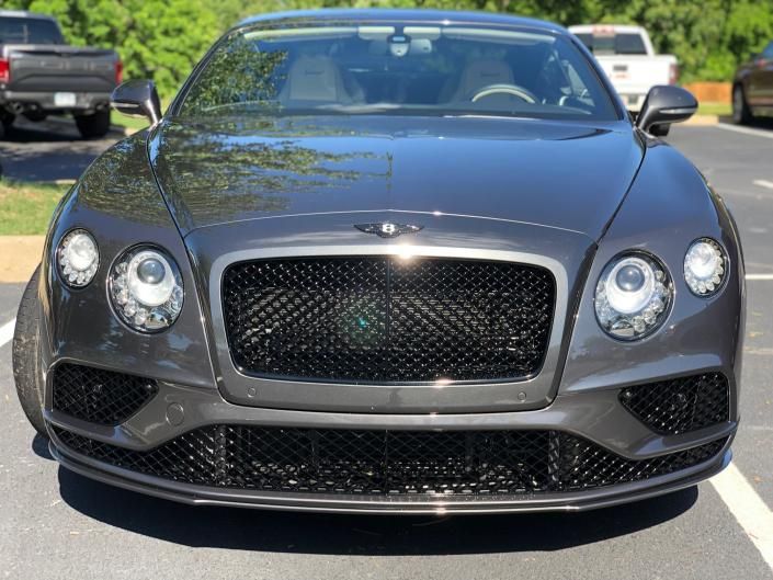Front view of a gray Bentley coupe parked outdoors in bright sunlight
