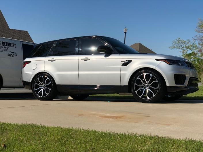 White Range Rover parked in a driveway, side view, with black tinted windows and rims.