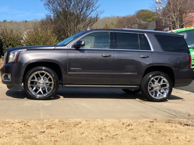 Gray GMC SUV parked on a driveway in bright sunlight, side view