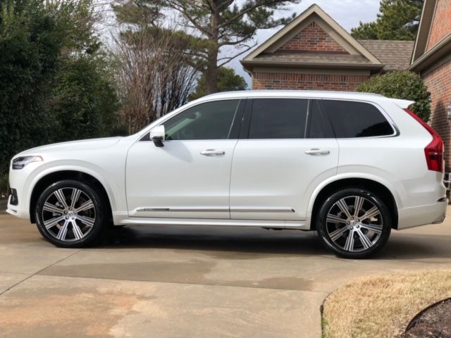 White SUV parked in a driveway beside a brick house