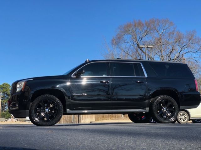 Black SUV parked outdoors under a clear blue sky with leafless trees in the background