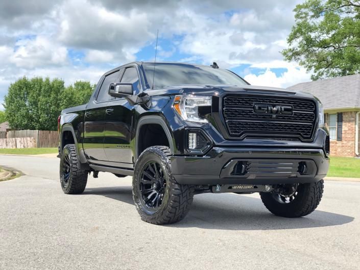Black lifted pickup truck parked on a suburban street under a cloudy sky