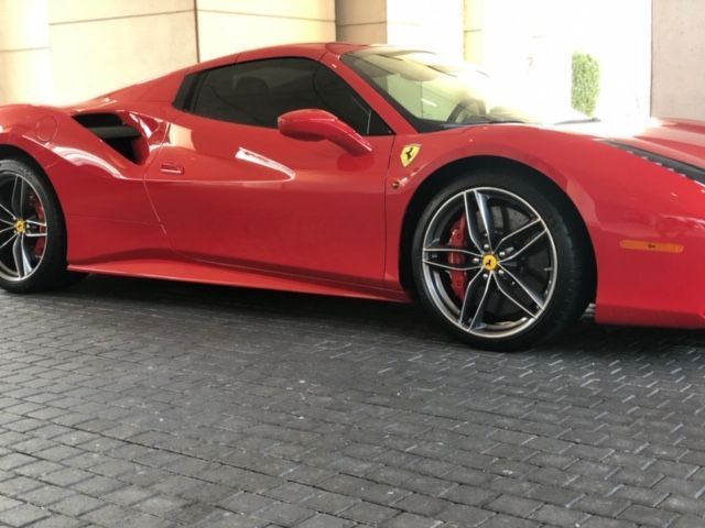 Red Ferrari sports car parked on a paved driveway under a covered area
