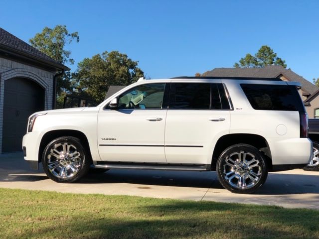White SUV parked in a driveway beside a house on a sunny day
