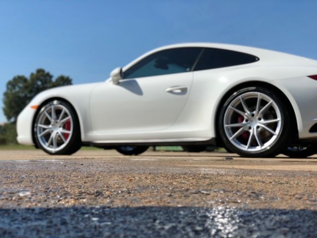 White sports car parked on a gravel road under a blue sky
