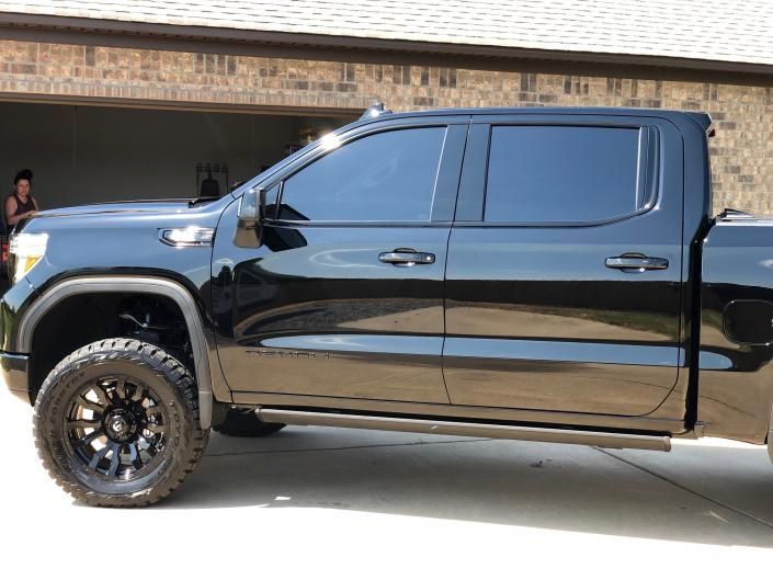 Black lifted pickup truck parked in a driveway, side view