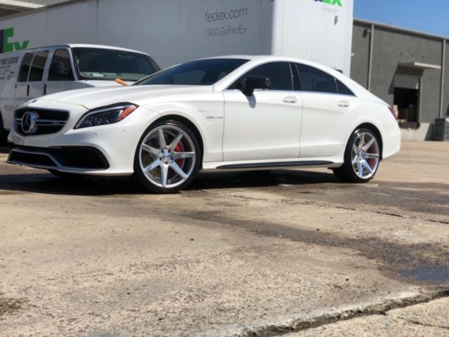White Mercedes sedan parked outside a dealership building on a sunny day