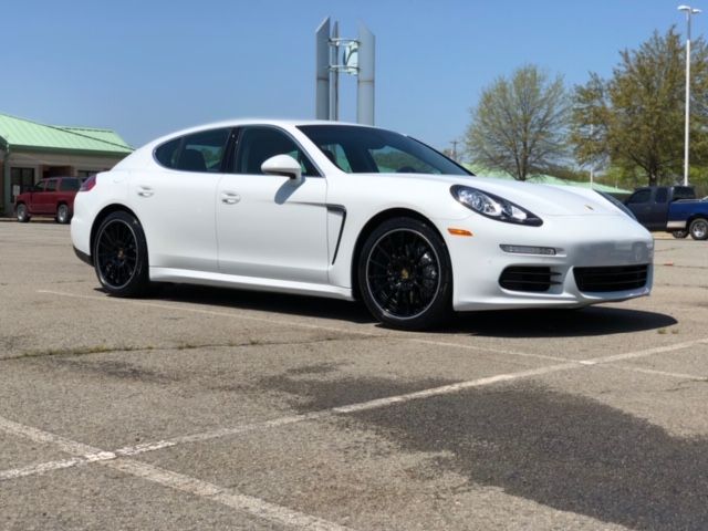 White Porsche sports car parked in a lot, side view, with a building and trees in the background