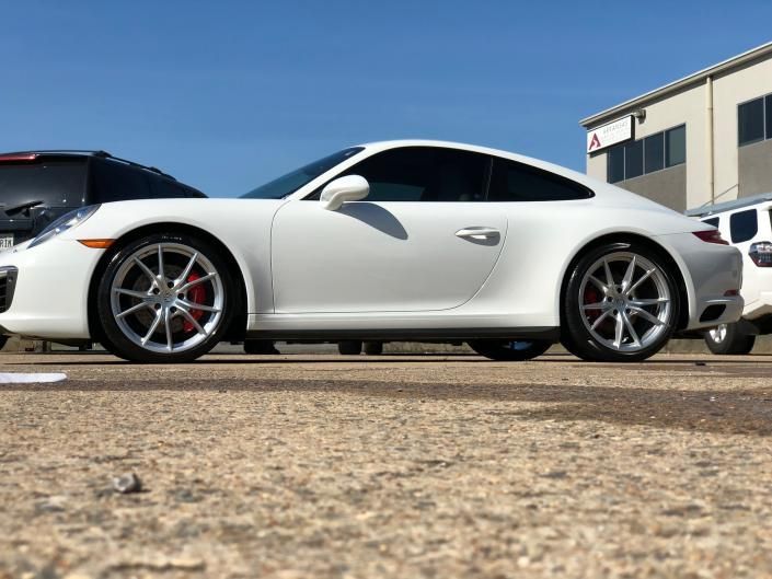 White sports car parked outdoors beside a building under a clear blue sky.